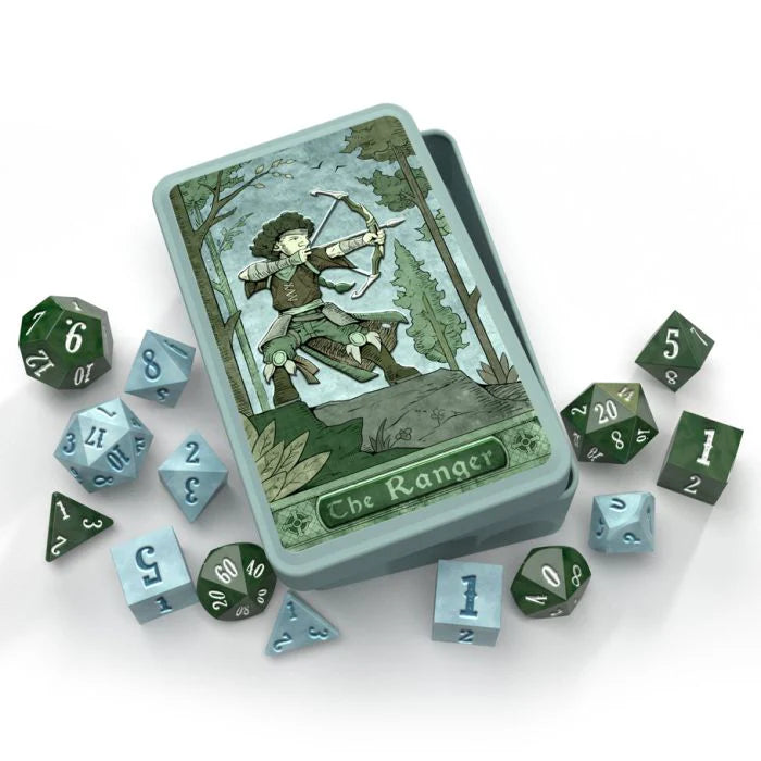 A set of dice in various colors including green, blue, gray, and white, with a tin box featuring a tarot-style illustration of a ranger.